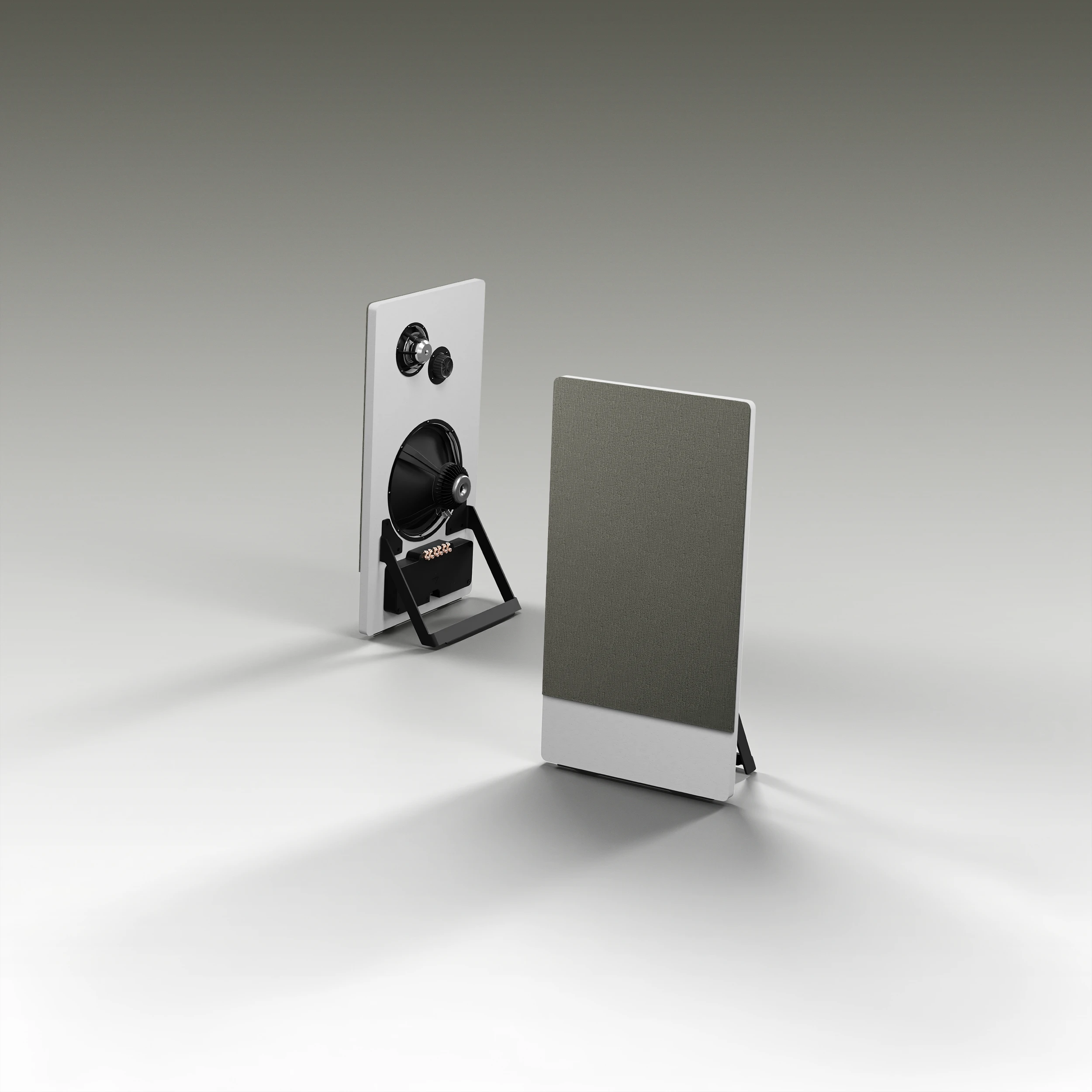 Two modern rectangular speakers with one showing front fabric cover and the other exposing black cone drivers and stand on a light gray surface.